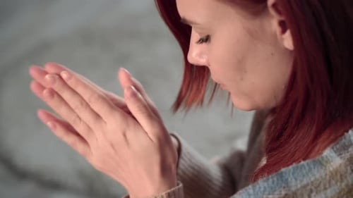 Une jeune femme par temps froid se réchauffe les mains alors qu'elle est assise dans une couverture chaude sur un canapé en gros plan