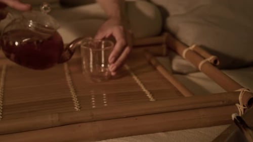 Pouring Tea into a Glass by Candlelight