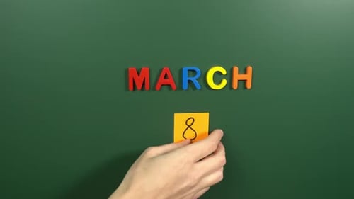 Hand sticking a sticker 8 March calendar day on school board. 8 date of March. Eighth day March
