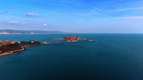 Wir nähern uns einer stark bewohnten Insel mit Häusern mit roten Dächern, die durch einen Damm mit dem Festland verbunden sind.