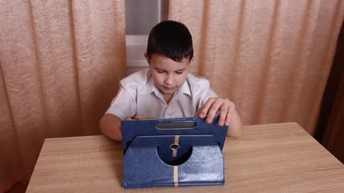 Boy Using Tablet Device at Desk Indoors