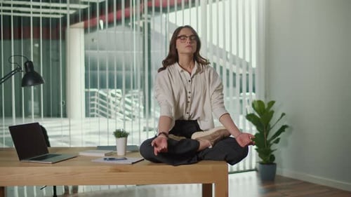 Woman Meditating on Desk in Bright Modern Office