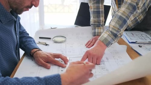 Architects Collaborating on Blueprints in a Modern Office