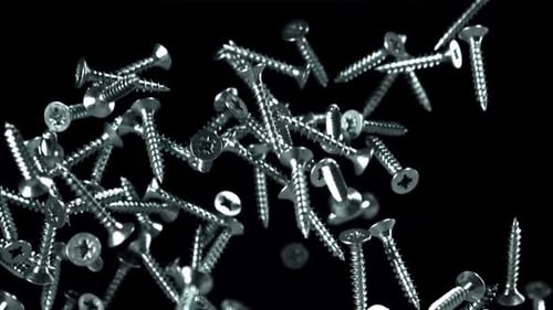 Scattered Silver Screws Falling on Black Background