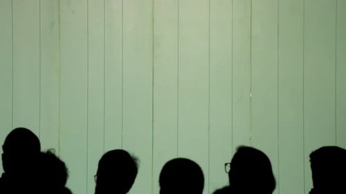 Silhouettes of audience watching a play. Panoramic plane shift right