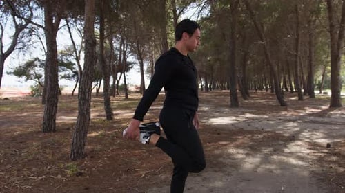 Man Dressed In Black Does Stretching In A Public Park
