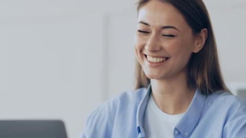 Young Woman Smiling at Her Laptop While Working From Home in a Cozy Setting