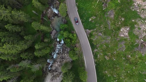 Scenic Drive Along a Winding Road Next to a Lush Forest and Flowing Stream