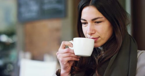 One morning a beautiful elegant woman eats breakfast at the outdoor bar with a coffee and croissan
