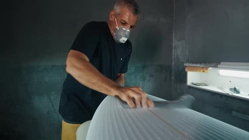 Surfbrettfabrik. Ein erwachsener männlicher Shaper stellt das Surfbrett in der Fabrik her