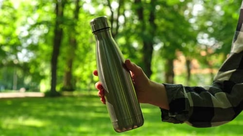 Closeup of Unrecognizable Female Hand Holding Water Bottle Reusable Steel Thermo Water Bottle in
