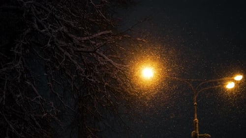 Thick Snowfall Glowing Under a Street Lamp at Night Warm Light Illuminating Snowladen Branches and