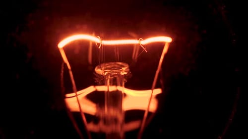 Light Bulb Starts Glow At Night. Dirty Filament Lamp Glass With Scratches Evokes Horror. Bright Glow