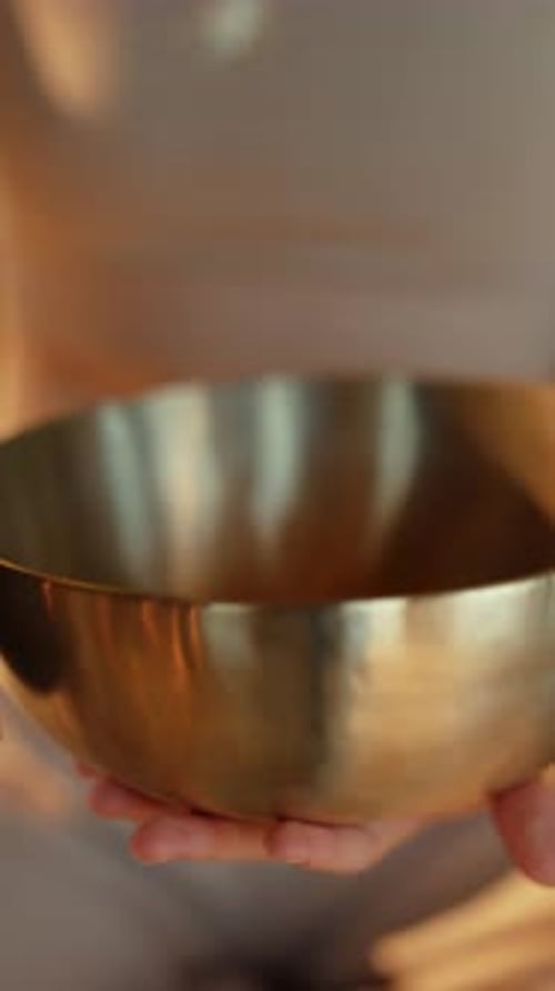 Person using singing bowl for sound bath therapy