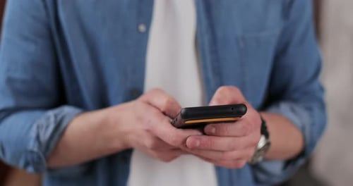 Man Messaging on Mobile Phone Wearing Denim Shirt