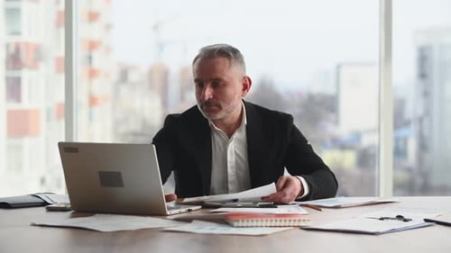 A Closeup of a Male Businessman Sitting in My Office Looking Through His Company's Financial
