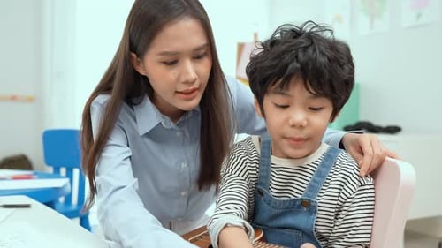 Teacher Helps Young Boy with Guitar at School