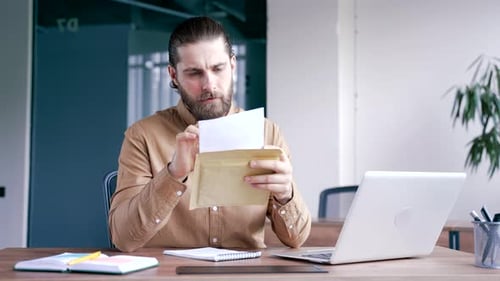 Upset disappointed businessman reading a letter with bad news sitting in a business office. Worried