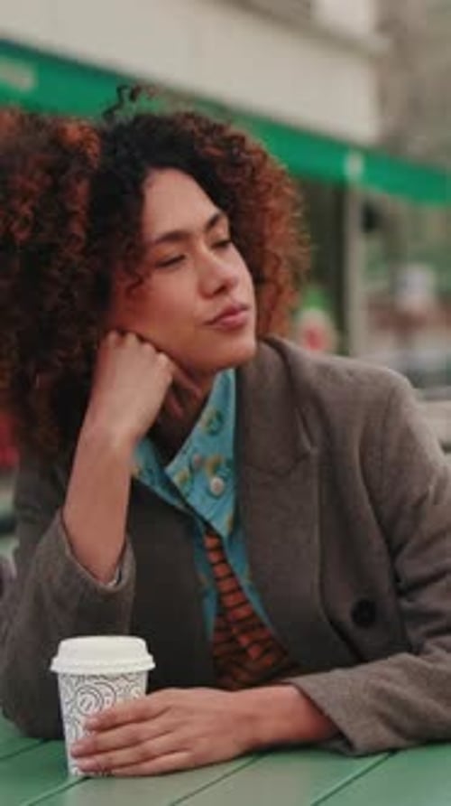 Vertical video, Thoughtful Woman Sits at Outdoor Cafe