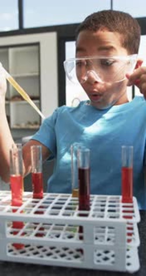 Vertical video: In school, child conducting science experiment with test tubes and pipette