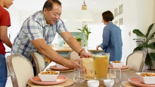 Family Setting Table For Dinner Together