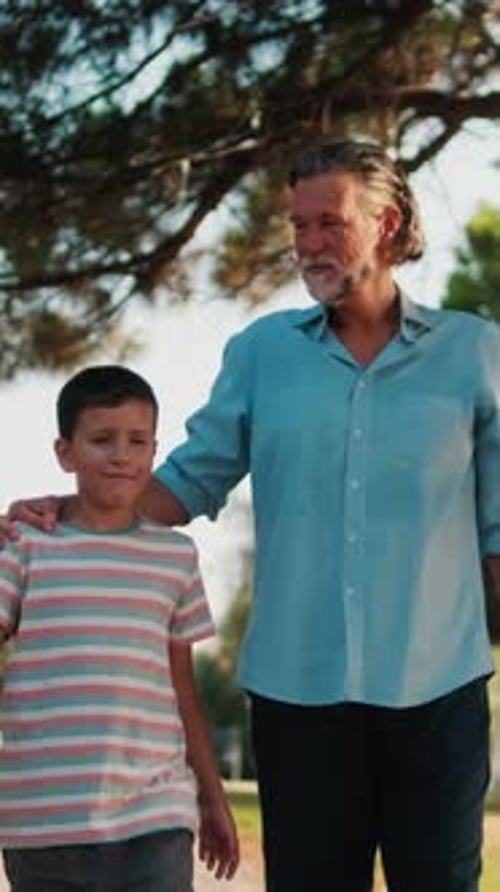 Vertical video, Grandfather And Grandson Walking In The Park