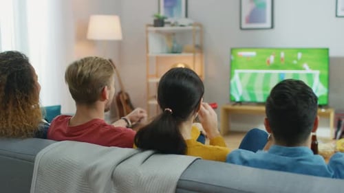Friends watching sports game on TV at home