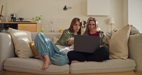 Concentrated Brunette Girl Tells Her Mother in Glasses How to Work on a Laptop and Gives Advice