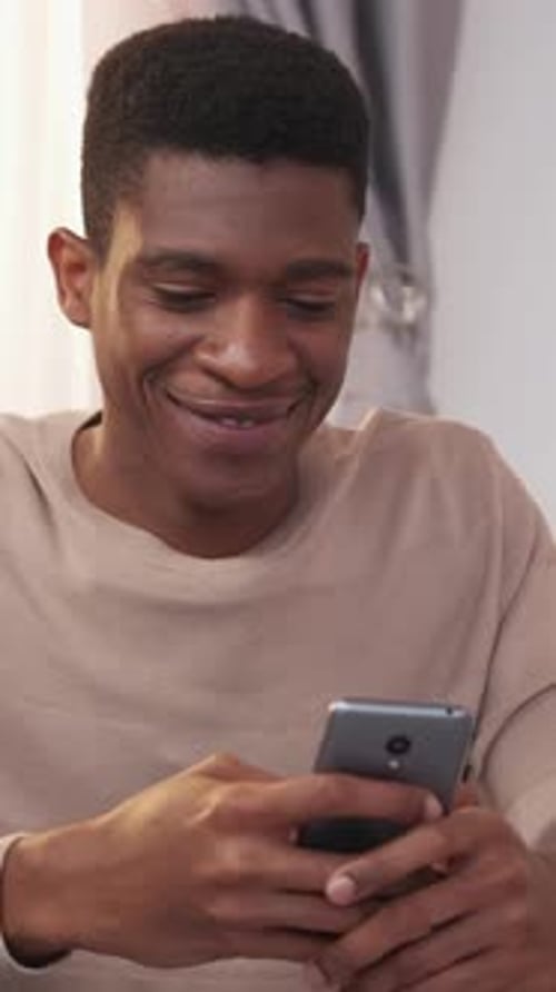 Man Smiling While Using Smart Phone Indoors
