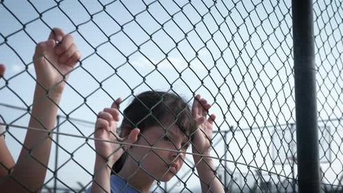 Two Young Girls Behind Chain Link Fence