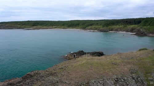 Woman at a scenic rocky shore surrounded by turquoise sea waters