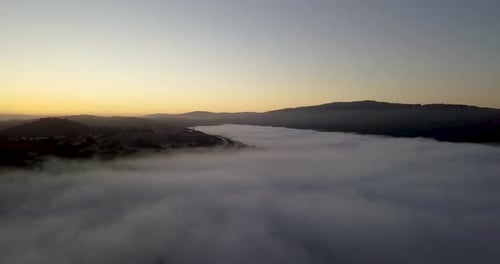Misty mountain Valley filled with fog clouds during sunrise with golden gradient sky camera turning