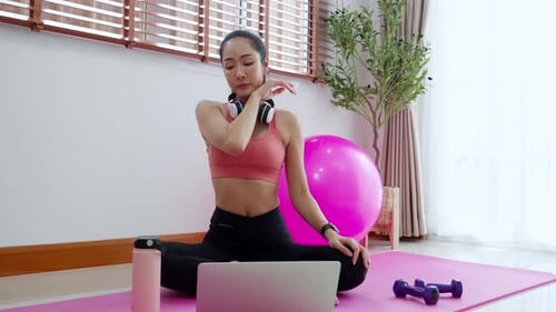 Woman on Yoga Mat Drinks Water after Exercise