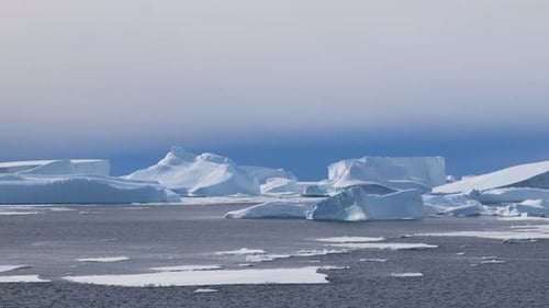 Riesige Eisberge schwimmen im kalten blauen Wasser unter dem riesigen Polarhimmel
