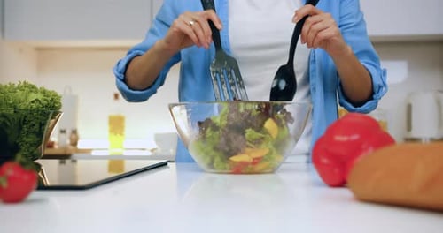 Close up of woman hands which mixing vegetable salad in glass bowl for breakfast or dinner