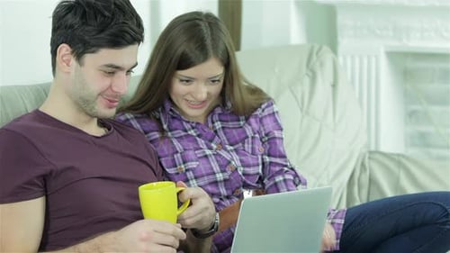 Young Couple Enjoys Laptop Together on Sofa