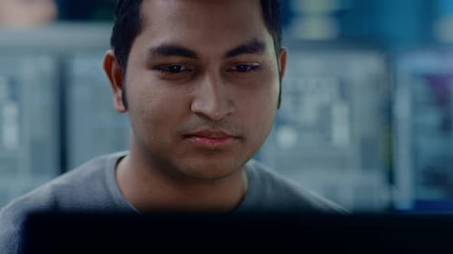 Portrait of a Smart and Handsome IT Specialist Working on a Personal Computer. In the Background Un