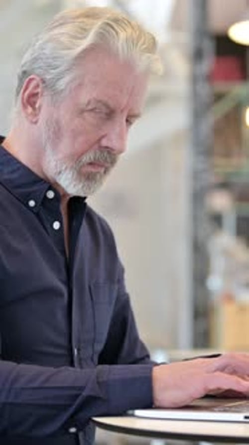 Old Man with Laptop Looking at Camera in Cafe, vertical video