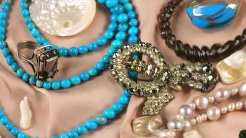 Jewelry made of precious stones and pearls on a beige silk background underwater