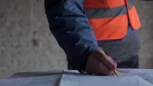 Um engenheiro de construção está examinando os desenhos de trabalho de um prédio alto.