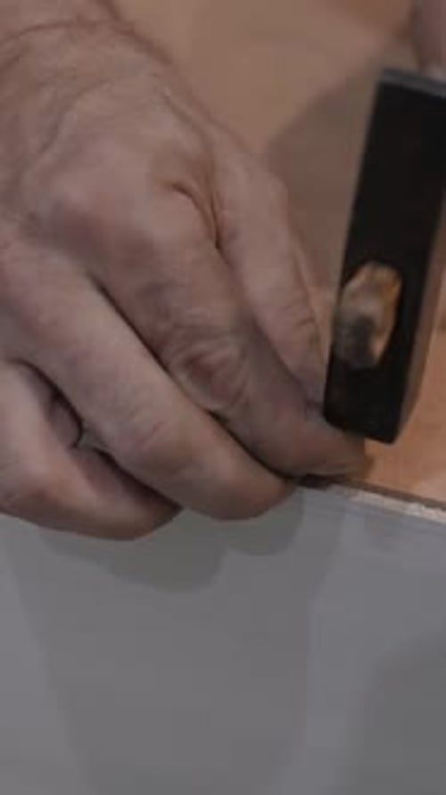 Hands Hammering Nail into Wood Furniture Close Up