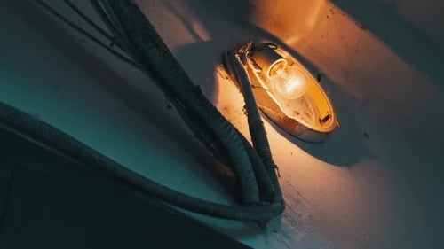 Old Incandescent Light Bulb Glows on the Concrete Wall in the Stairwell