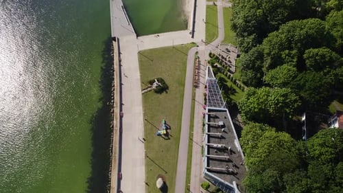 Aerial birds eye shot of walking people on Promenade in Gdynia with sun reflection in water