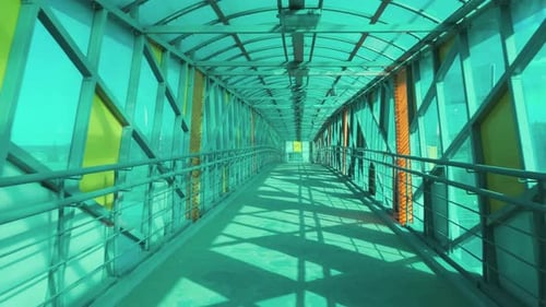 Walking inside empty footbridge. Glass pedestrian tunnel without people