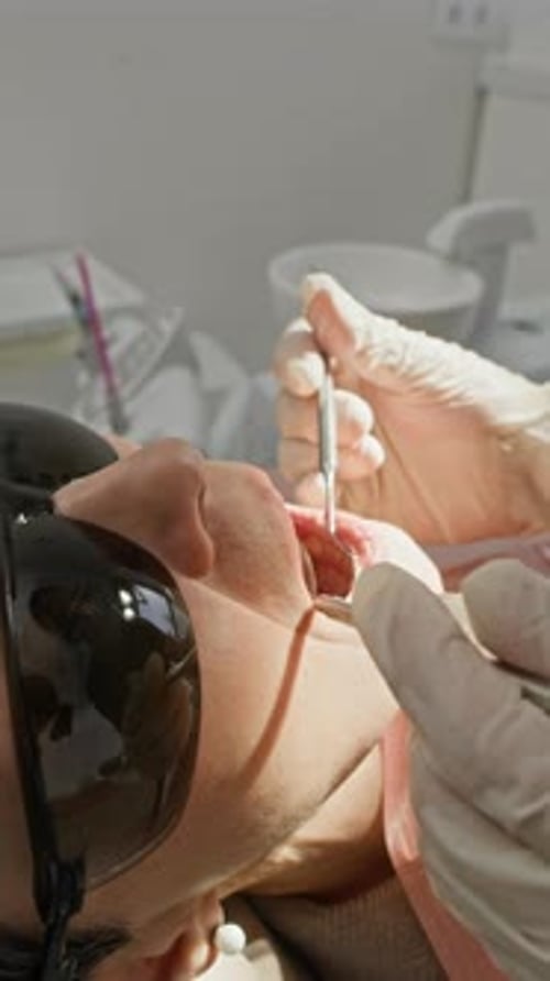 Dentist Examining Patient in Clinic with Tools
