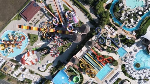 Aerial Footage of a Vibrant Water Park with Colorful Slides Lazy River Pools and Sun Loungers