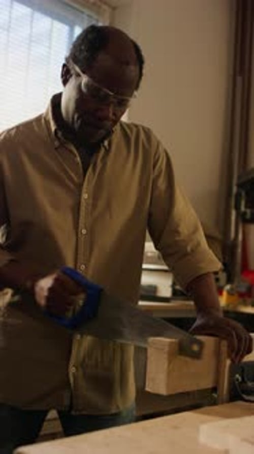 Carpenter Cutting Wood Piece with Handsaw