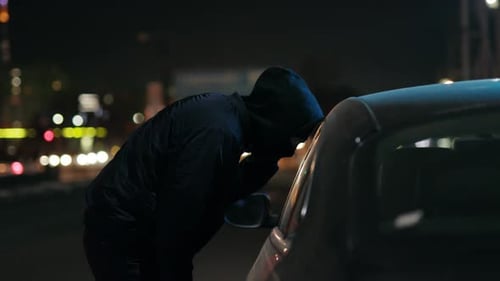 Figure Breaking into Car at Night