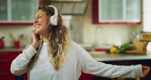 Authentic close up shot of an young carefree happy woman wearing white headphones is having fun to