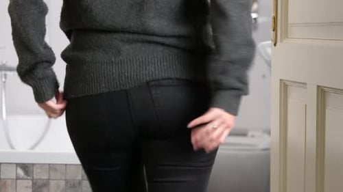 Woman in front of toilet clutches her butt because of sudden strong pain in anus area. Sign of Hemor